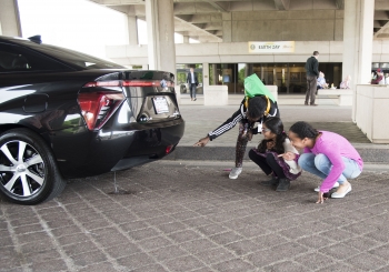 Children watch as water is produced by a hydrogen fuel cell car.