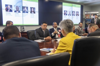 Honorable Director Campos at the conference table speaking with participants