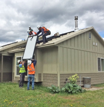 Team of people installing solar panels on a house.