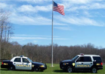 Photo of two police cars and an American flag behind.