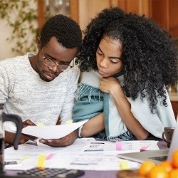 Two people reviewing documents that are laid out on a table.