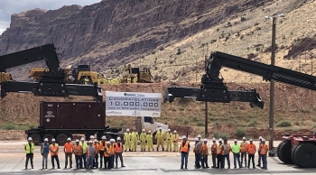EM Moab Uranium Mill Tailings Remedial Action Project employees gather around project equipment after loading the 10 millionth ton of uranium mill tailings into a container to be shipped by train to the Crescent Junction disposal cell.