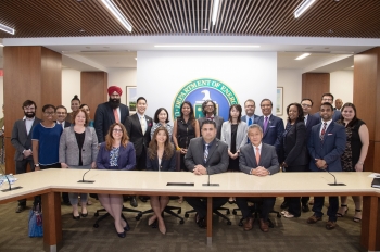 The approx 25 attendees and panelists pose in front of the Department of Energy seal.