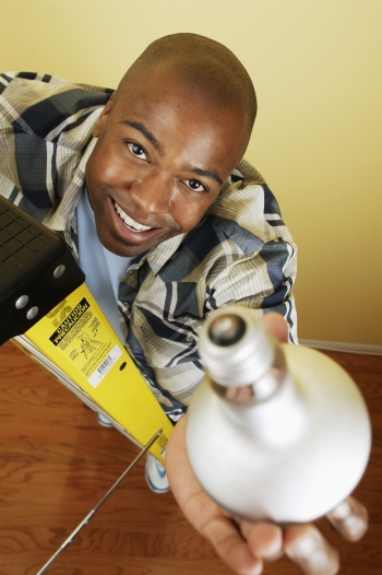 A young man holds a lightbulb up in the air.