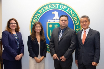 Speakers stand in front of the DOE seal