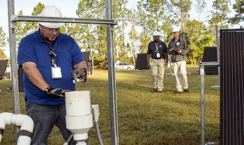 Savannah River Nuclear Solutions (SRNS) Mechanic Thad Ashely, foreground, checks components of a soil vapor extraction unit, as SRNS engineers Joao Cardoso-Neto, background, left, and John Bradley inspect solar panels.