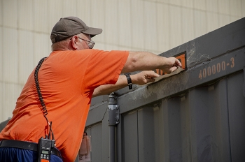 Damon Cates applies labels on a shipping container in preparation for the first cold trap leaving the EM Paducah Site.