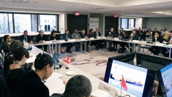 Large group of people seated around a room in a square-shaped configuration of tables, at IFNEC Week 2019 in Washington, D.C.