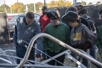 Michael Meyer, left, welding instructor at Evans High School, and welding students examine the donated stainless steel from SRS.