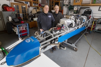 Sandia National Laboratoriesâ Joel Wirth, left, and his father and labs retiree Jack Wirth stand next to their dismantled roadster in Joel Wirthâs home garage. Between racing seasons, the car undergoes extensive repairs.