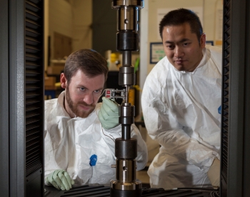Aaron Bales, left, and Rob Panaro attach an extensometer to a tensile specimen. The extensometer gives an accurate measure of how much the specimen stretches during a tensile test.