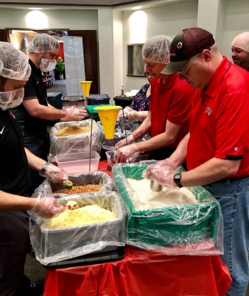 Michael Plinski, right, and the UNLV Alumni Legacy Board making meals to support a local food bank.