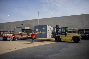 Paducah Site contractor maintenance mechanic Matt Wheeler spots Heavy Equipment Operator Ryan Jackson as a cold trap is lowered onto a shipping trailer outside the storage facility.