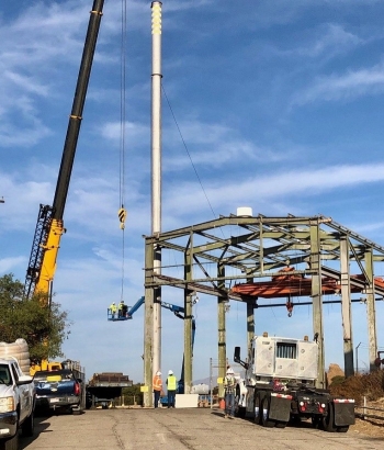 A crew tears down a stack attached to Building 4022 at the Radioactive Materials Handling Facility (RMHF) at the Energy Technology Engineering Center. Teardown of the structure marked the completion of demolition of a set of 10 buildings at the RMHF.