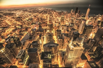 A large waterfront city at night, with bright yellow lights in the street.