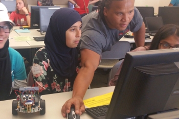 An undergraduate student shows high schoolers how to program their robotic rover system using an open-source platform called Arduino