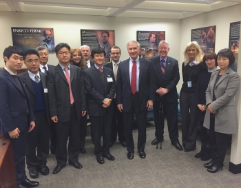 Photo of a group of people in business suits standing in a meeting room, facing the camera.
