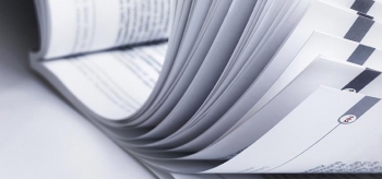 Black and white photo of pages in a book being flipped through.