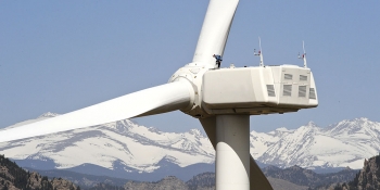 A wind turbine with mountains in the background.