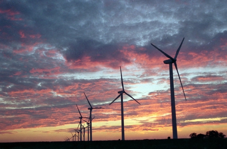 Utility-scale wind turbines against a sunset sky.