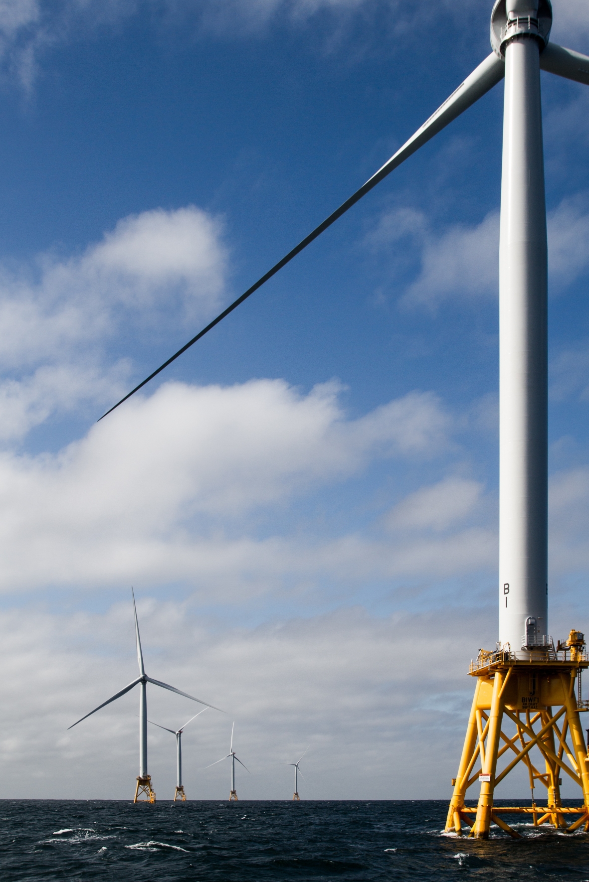 Photo of several offshore wind turbines in the ocean.